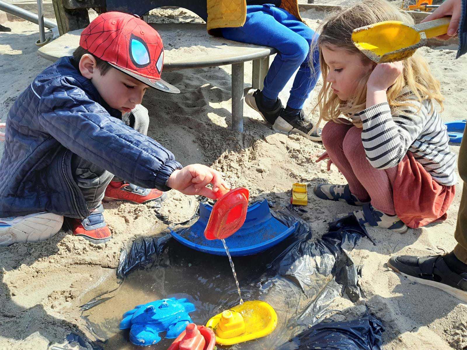 Børn leger med vand i sandkassen - det er sjovt at eksperimentere med vand og sand