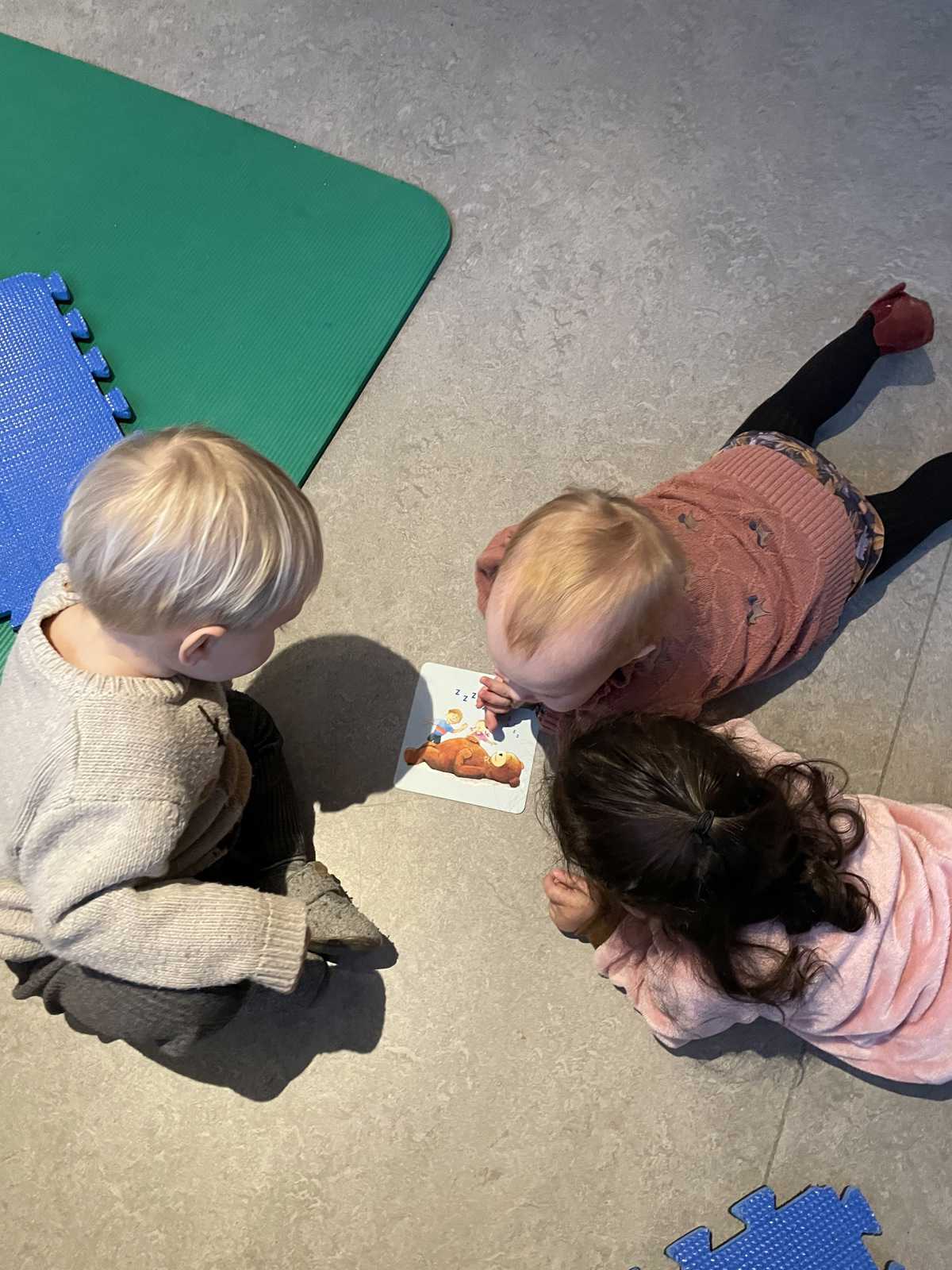Børn ser på et billede af sangen "Bjørnen sover" - vi synger mange sange med og for børnene